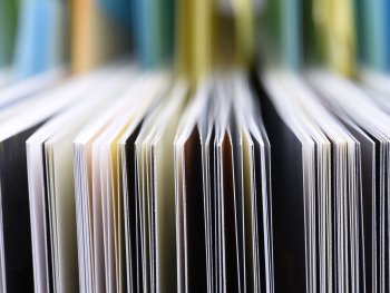 Copyright: AdobeStock Nahaufnahme einer Reihe aneinandergereihter Bücher mit bunten Einbänden.