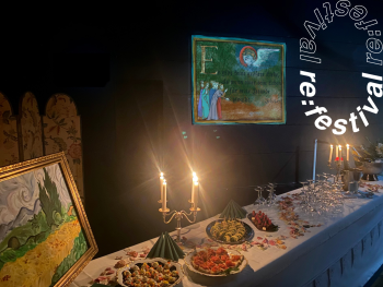 Festlich gedeckter Tisch mit Kerzenleuchtern, Fingerfood und Gläsern vor einem beleuchteten Bild mit religiöser Illustration, daneben ein Gemälde mit Zypressenlandschaft.
