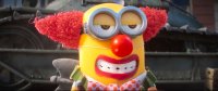 Animierte Filmfigur, ein gelbes Minion, als Clown verkleidet mit roter Perücke, roter Nase und geschminktem Mund.