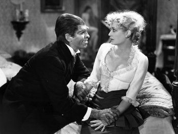 Copyright: Filmverleih
Schwarz-Weiß-Filmszene, in der ein Mann in Anzug einer Frau in Rüschenbluse eindringlich die Hände hält, während sie ihn anblickt.