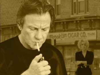 Copyright: Filmverleih
Filmplakat „Smoke“ in Sepiatönen: Ein Mann zündet sich vor einem Zigarrenladen eine Zigarette an, im Hintergrund geht eine Frau vorbei.