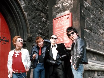 Copyright: Filmverleih
Vier Personen in Punk- und Rockabilly-Kleidung mit Sonnenbrillen und Lederjacken posieren vor dem Eingang einer Kirche.