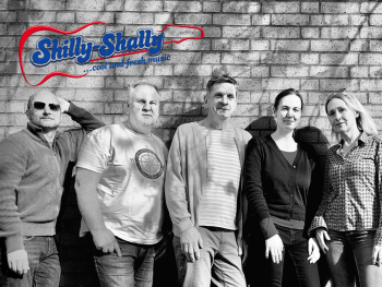 Sechs Personen der Band Shilly-Shally stehen in Schwarz-Weiß vor einer Backsteinwand, oben links das Logo mit dem Slogan „…cool and fresh music“.