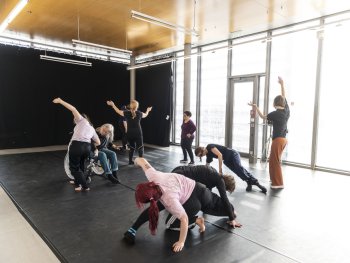 Foto: Brigitte Sauer
Mehrere Personen tanzen in unterschiedlichen Körperhaltungen in einem hellen Studio mit großen Fensterfronten.
