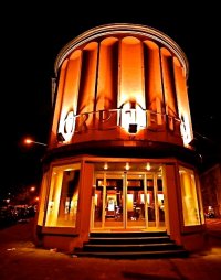 Nachts orange beleuchtete, runde Fassade des Kinos „Orpheum“ im Art-déco-Stil mit beleuchtetem Eingangsbereich.