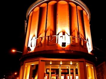 Nachts orange beleuchtete, runde Fassade des Kinos „Orpheum“ im Art-déco-Stil mit beleuchtetem Eingangsbereich.