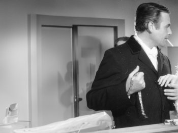 Copyright: Filmverleih
Schwarz-Weiß-Filmszene: Ein Mann im Anzug mit Zigarette hält eine Halskette und steht einer Frau in einem Federmantel gegenüber, die ihn ansieht.