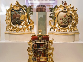 Drei aufwendig verzierte Wappen werden präsentiert.