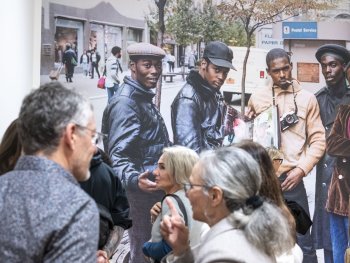 Besucherinnen und Besucher stehen in einer Ausstellung vor einer großformatigen Fotografie, die fünf Männer in einer Straße einer Großstadt zeigt.