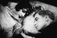 Schwarz-Weiß-Filmszene mit einer Frau und einem Mann, die nebeneinander liegend ein intensives Gespräch führen.