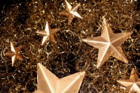 Goldene Sterne liegen zwischen gekräuselten goldfarbenen Dekodrähten.