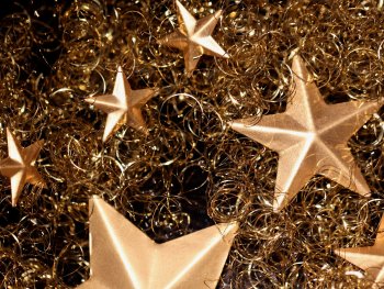 Copyright: nennieinszweidrei auf pixabay Goldene Sterne liegen zwischen gekräuselten goldfarbenen Dekodrähten.