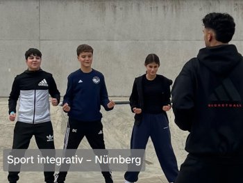 Drei Jugendliche in Sportkleidung trainieren mit geballten Fäusten, während eine Trainerperson vor ihnen steht, Bildtitel „Sport integrativ – Nürnberg“.