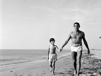 Copyright: Filmverleih
Schwarz-Weiß-Foto eines Mannes und eines Jungen in Badehosen, die händchenhaltend am Strand entlang spazieren.