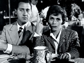Copyright: Filmverleih Zwei Personen sitzen an einem Restauranttisch, eine hebt mit ernster Miene den Zeigefinger, im Hintergrund ein Kellner.