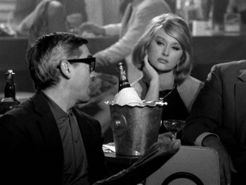 Copyright: Filmverleih
Schwarz-Weiß-Filmszene mit zwei Männern in Anzügen und einer Frau an einem Tisch mit Champagnerkühler in einer Bar.