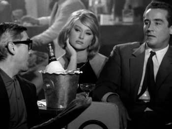 Copyright: Filmverleih Schwarz-Weiß-Filmszene mit zwei Männern in Anzügen und einer Frau an einem Tisch mit Champagnerkühler in einer Bar.