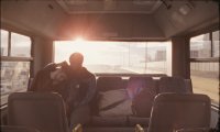 Person sitzt im Gegenlicht der untergehenden Sonne in einem Bus und blickt aus der Fensterfront nach draußen.