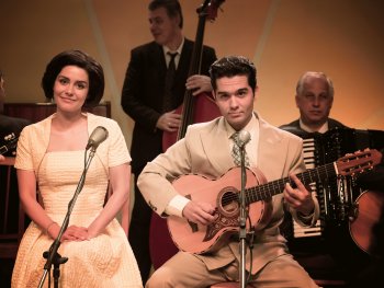 Copyright: Kinostar Filmverleih Eine Sängerin und ein Gitarrist im Stil der 1950er Jahre sitzen vor Mikrofonen auf einer Bühne, umgeben von einer Band mit Kontrabass und Akkordeon.