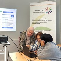 Frau zeigt Frauen etwas an einem Laptop