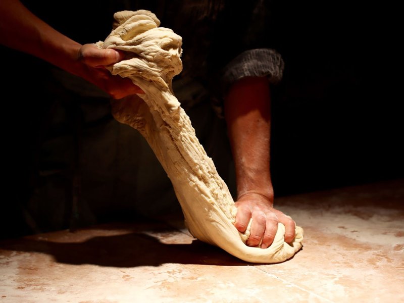 Close-up shot of two hands kneading and stretching dough.
