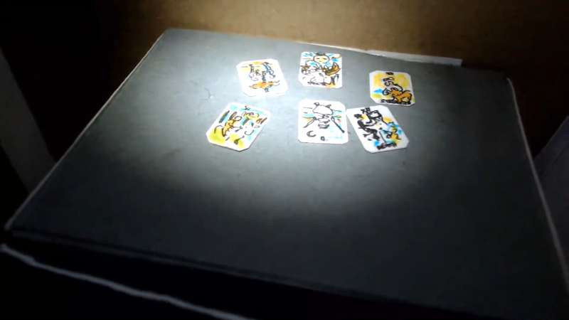 Dunkler Tisch auf dem sechs Spielkarten liegen, die von einem Spotlight erhellt werden.