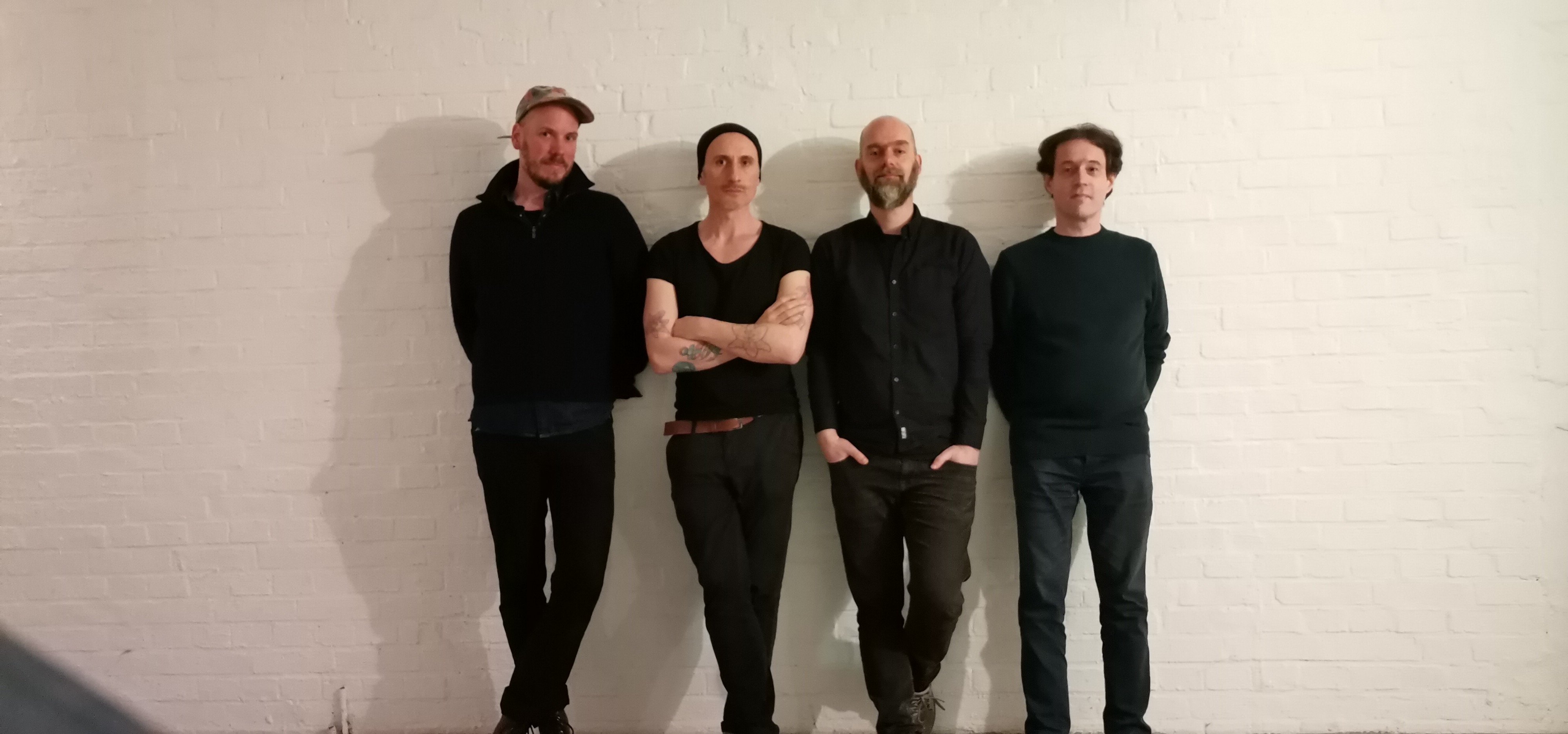 4 Männer vor einer weißen Wand