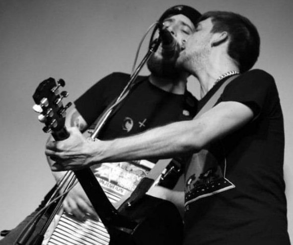 2 Männer, einer an der Gitarre und einer mit Waschbrett, singen in ein Mikrophon