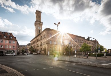 Das Rathaus von Fürth mit hohem Turm bei Sonnenlicht, umgeben von Straßen und Gebäuden in der Innenstadt.
