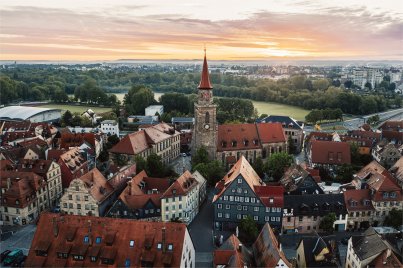 Luftaufnahme der Altstadt mit der Kirche St. Michael im Zentrum, umgeben von historischen Fachwerkhäusern bei Sonnenuntergang.