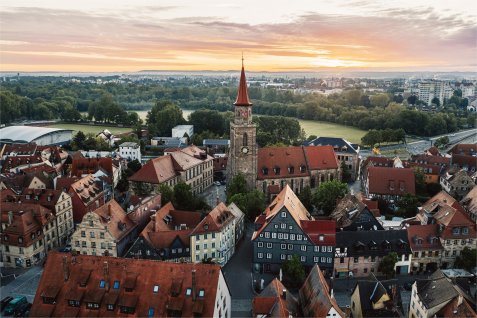Luftaufnahme der Altstadt mit der Kirche St. Michael im Zentrum, umgeben von historischen Fachwerkhäusern bei Sonnenuntergang.