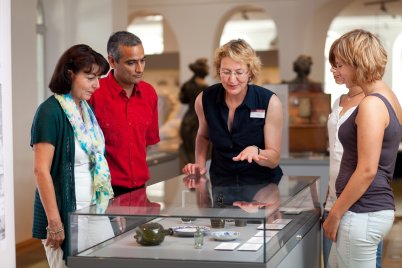 Stadtführerin erklärt einer Besuchergruppe Exponate in einer Museumsvitrine im Stadtmuseum Fürth.