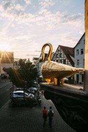Figur "Goldener Schwan" als Wirtshausausleger am Grünen Markt, im Hintergrund Fachwerkhaus