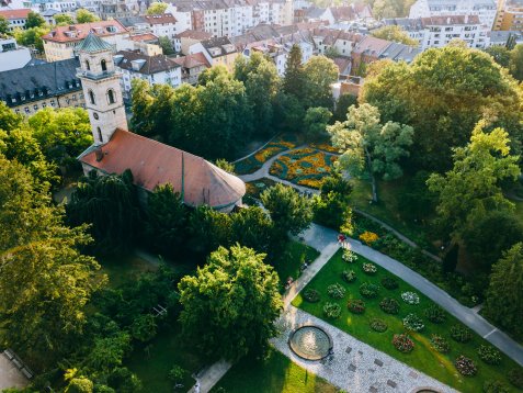 Luftaufnahme des Stadtparks mit der Auferstehungskirche, dem Empfangsgarten mit Blumenbeeten und dem Rosengarten mit Springbrunnen und Wegen.