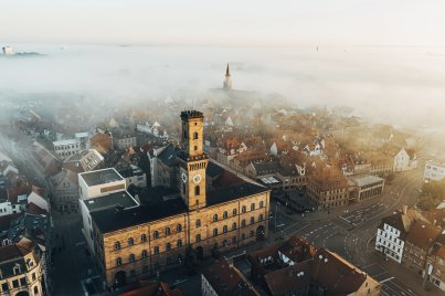 Luftaufnahme des Fürther Rathaus bei Nebel, im Hintergrund der Kirchturm von St. Michael, umgeben von Häusern und Straßen.