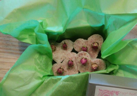 Herzförmige Seifen mit getrockneten Rosenknospen auf grünem Seidenpapier in einer Schachtel