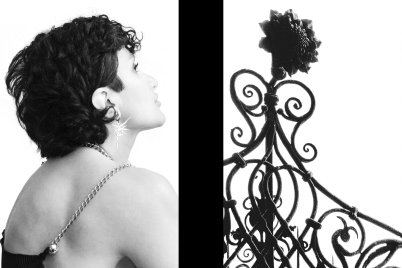 Schwarz-Weiß Fotografie aus der Serie "Transgression durch Hoffnung". Links eine junge Frau, Rückenansicht, in die Ferne blickend, Rechts ein kunstvoll gearbeitetes Metallgitter