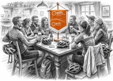 Bleistiftzeichnung einer Gruppe von Menschen an einem Holztisch in einer Bar mit Fahrradhelmen und einem Banner des Allgemeinen Deutschen Fahrrad-Clubs (ADFC) in der Mitte