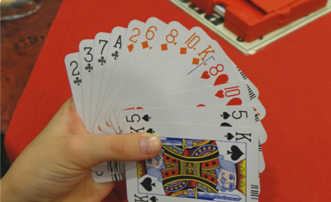 Hand hält Fächer aus Spielkarten mit verschiedenen Farben und Symbolen