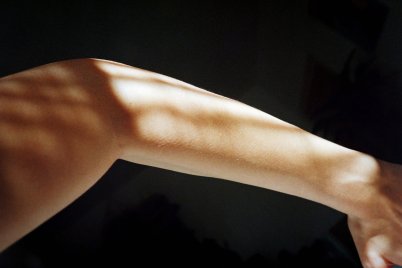 Bildausschnitt von einem Arm auf dem Sonnenlicht reflektiert vor dunklem Hintergrund.