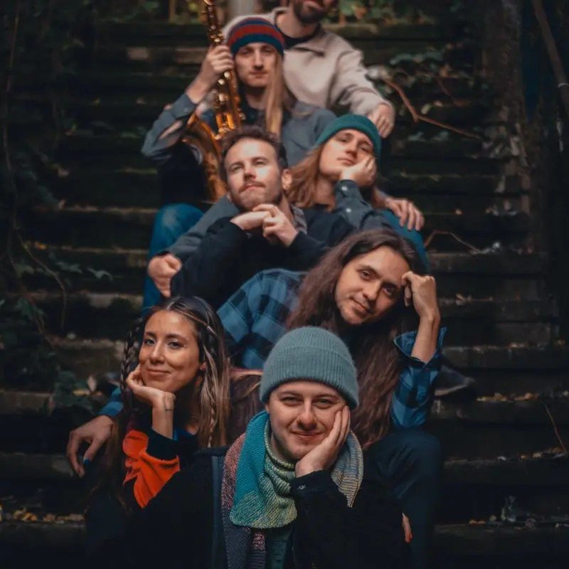 Bandfoto Taihr: 7 Personen sitzen auf einer Treppe