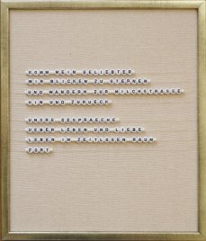 Text aus weißen Buchstabenperlen auf beigem Stoff in einem goldfarbenen Rahmen mit dem Text 'KOMM MEIN GELIEBTER WIR BLICKEN ZU STERNEN UND WANDERN ZUR MILCHSTRASSE HIN UND ZURUECK UNSRE GESPRAECHE UEBER LEBEN UND LIEBE LEBEN IM ZEITLOSEN RAUM FORT'
