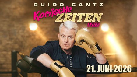 Guido Cantz mit goldfarbenen Boxhandschuhen vor unscharfem Hintergrund