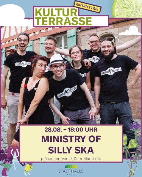 Gruppe von sieben Personen in schwarzer Kleidung mit "Ministry of Silly Ska"-Aufdrucken vor Backsteinmauer, einige lachen und haben die Arme ausgebreitet