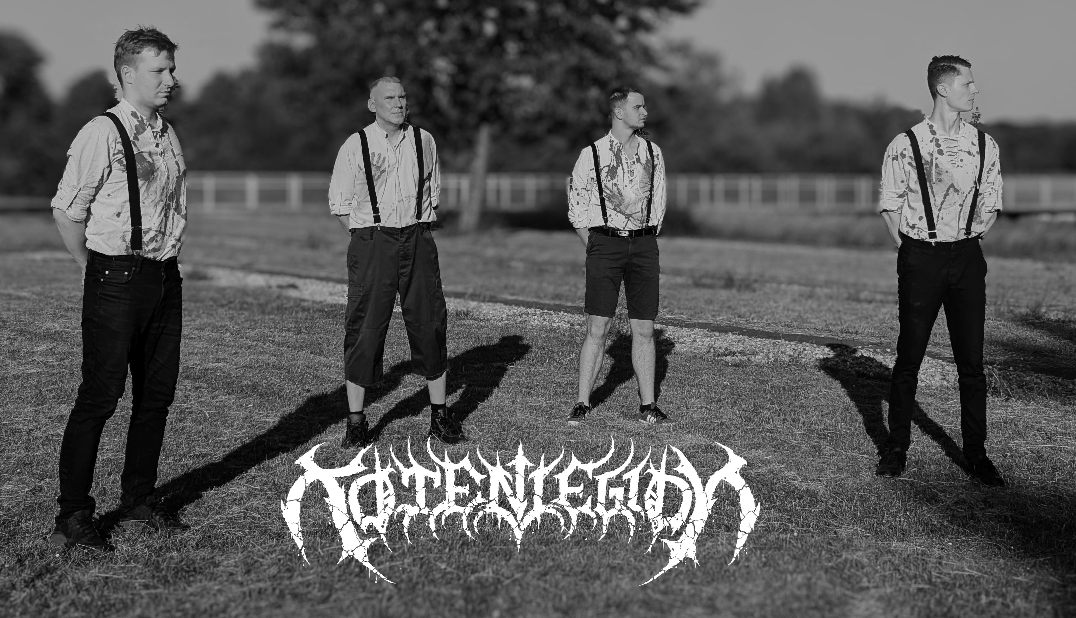 Schwarz-weißes Bandfoto von Totenlegion mit vier Personen in blutbefleckten Hemden mit Hosenträgern, die auf einer Wiese stehen.
