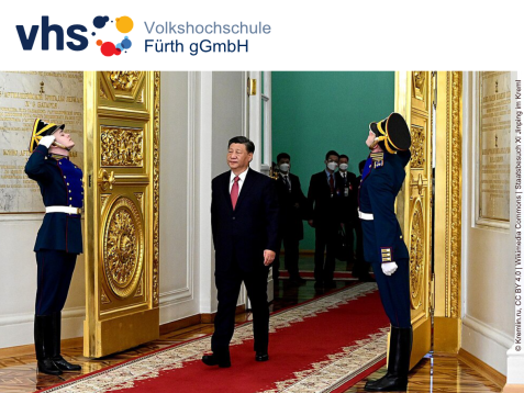 Xi Jinping schreitet durch eine goldverzierte Tür im Kreml, während zwei salutierende Ehrengardisten an den Seiten stehen.