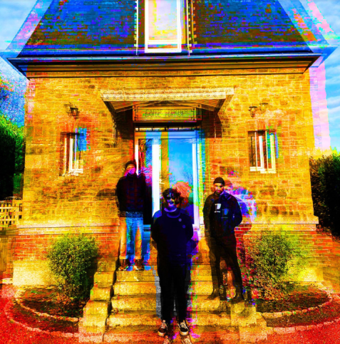 Drei Personen stehen auf der Treppe vor einem Steinhaus, das Bild ist in kräftigen, verfremdeten Farben mit Glitch-Effekt bearbeitet.