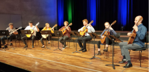 Die Gitarren- und   Lautenklasse der Hochschule für Musik Nürnberg: Vier Personen sitzen auf Stühlen auf einer Bühne