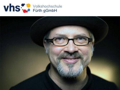 Porträt von Benjamin Krauss mit Hut, Brille und grauem Bart, darüber das Logo der Volkshochschule Fürth gGmbH.