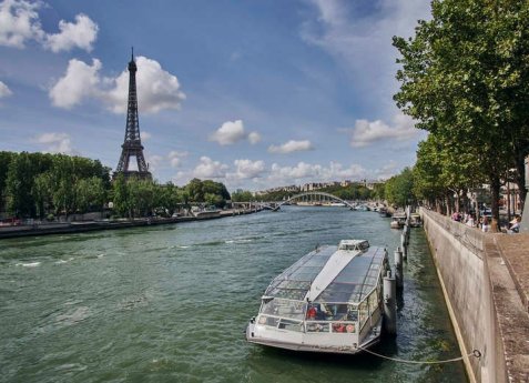 Ausflugsboot auf der Seine in Paris mit Blick auf den Eiffelturm im Hintergrund.